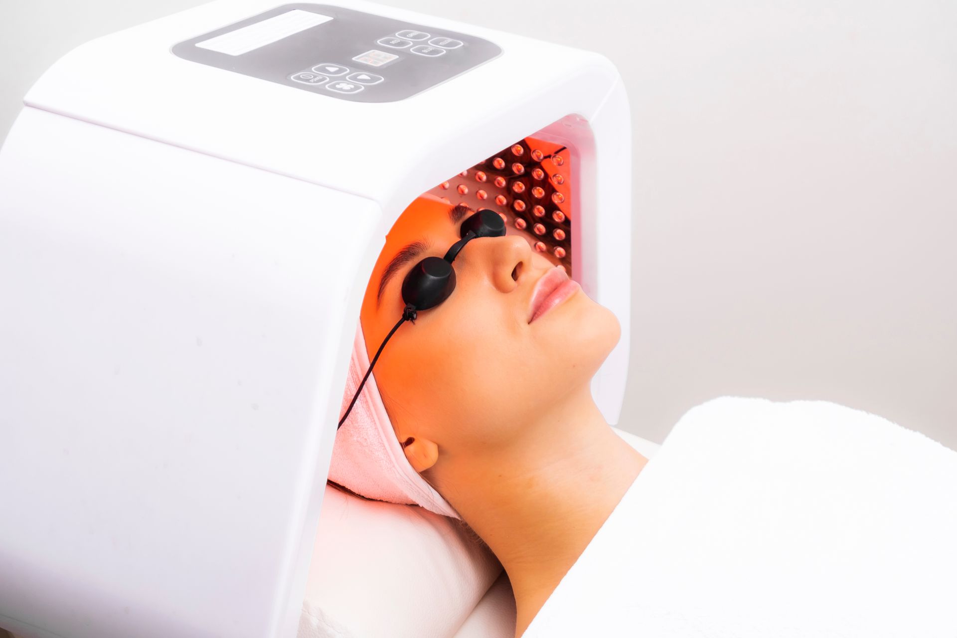 A woman is getting a light therapy treatment on her face.