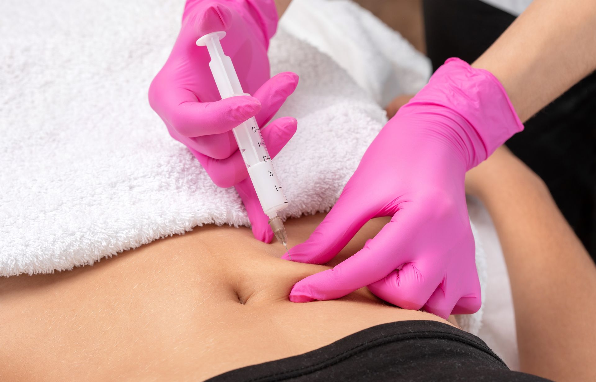 A woman is getting an injection in her stomach.