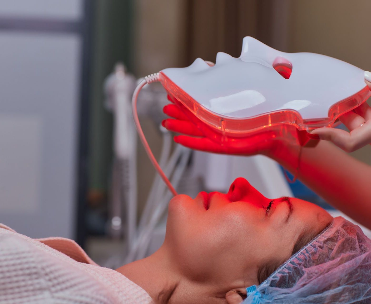 A woman is getting a red light treatment on her face.