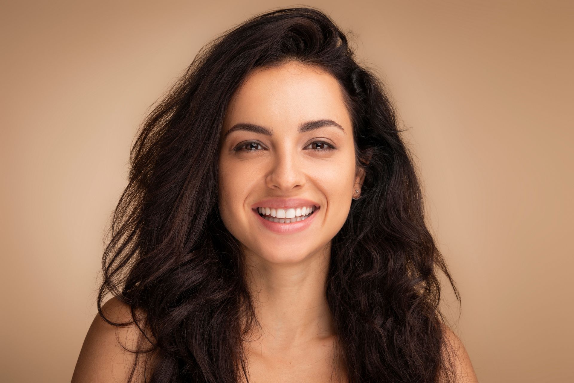 A woman with long dark hair is smiling for the camera.