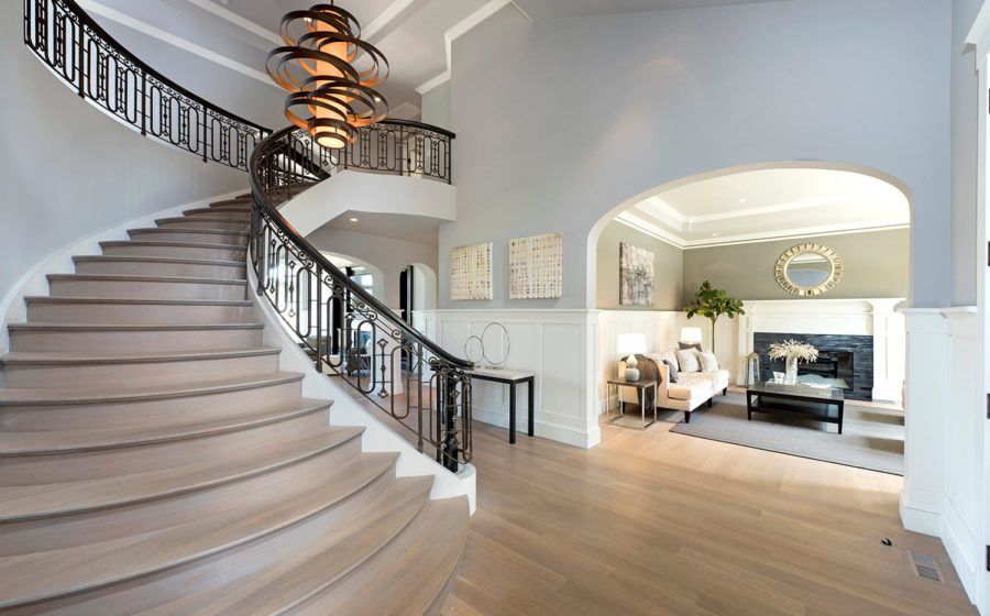 Elegant foyer with a curved staircase, chandelier, and open view into a bright living room
