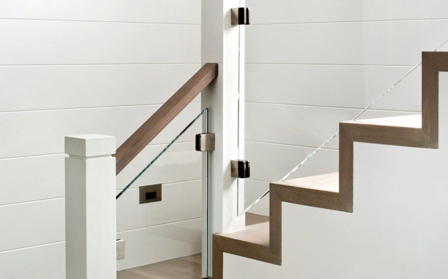 Modern staircase with glass railing and wooden handrail in a white interior