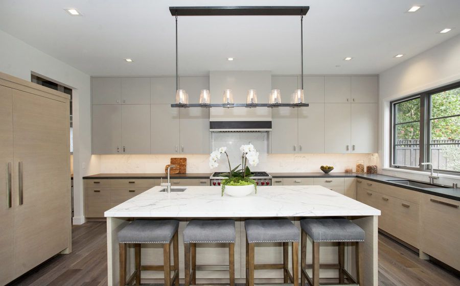 Modern kitchen with a large island, pendant lights, light wood cabinets, and a window by the sink.