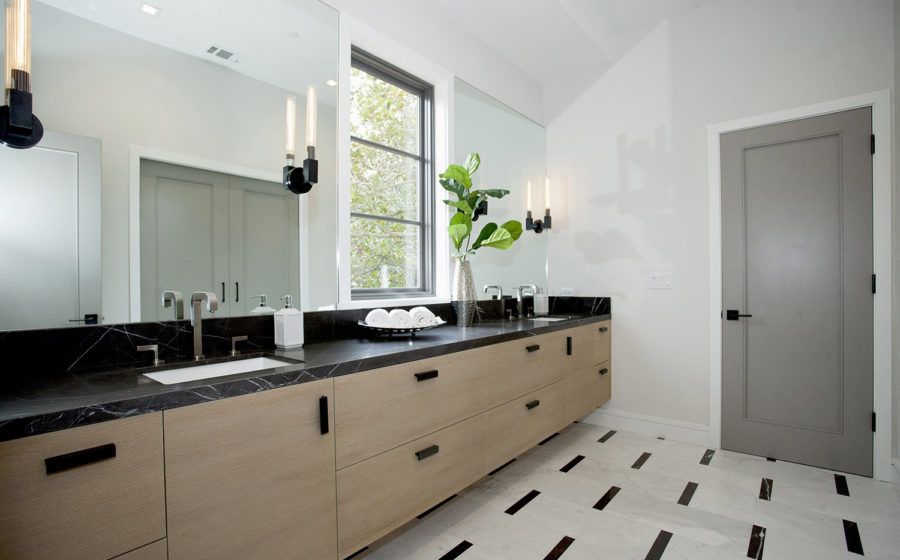Modern bathroom with double sink vanity, large mirror, white walls, black countertop, and tiled floor.