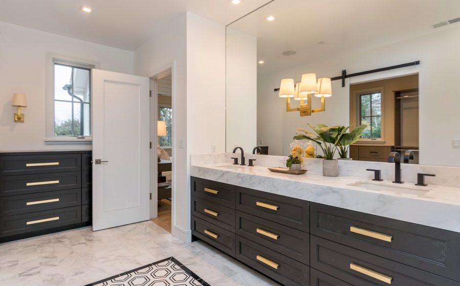 Modern bathroom with dark vanity, marble counters, large mirror, and black-and-white tile floor