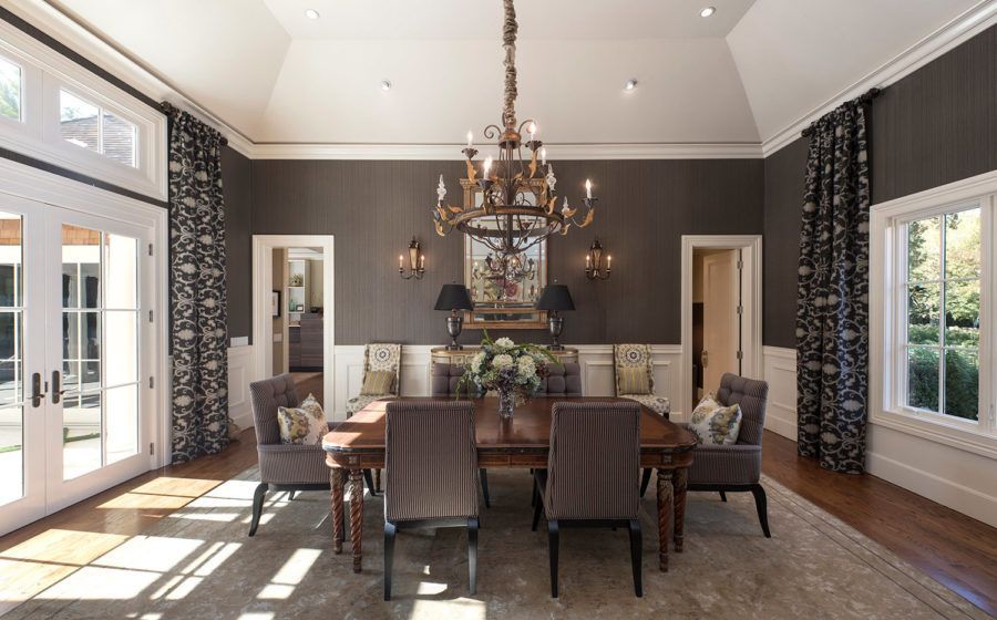 Elegant dining room with dark walls, chandelier, and large windows letting in daylight