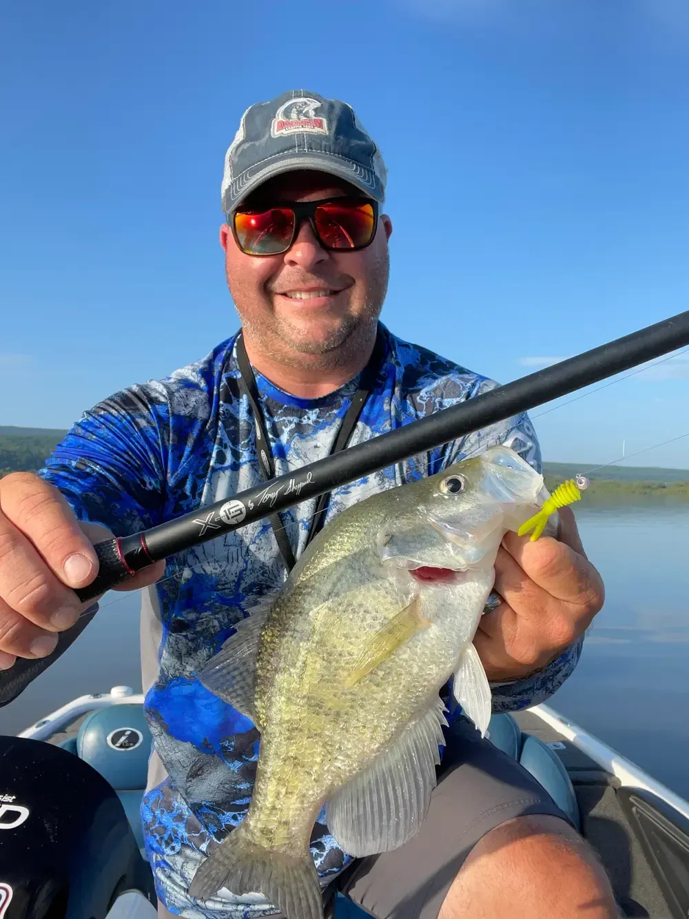 Keeping It Crappie Guide Service Fishing Charter in Lake Dardanelle Arkansas A man is sitting on a boat holding a fish and a fishing rod.