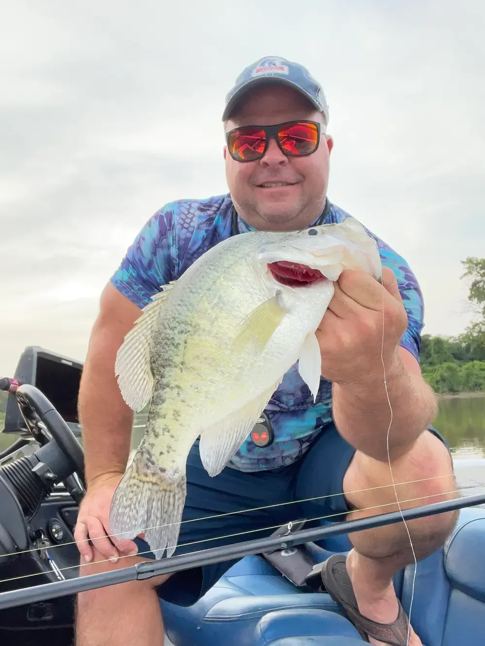 A man is sitting on a boat holding a large fish.