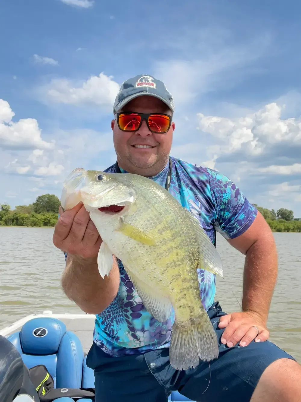 A man is sitting on a boat holding a large fish.