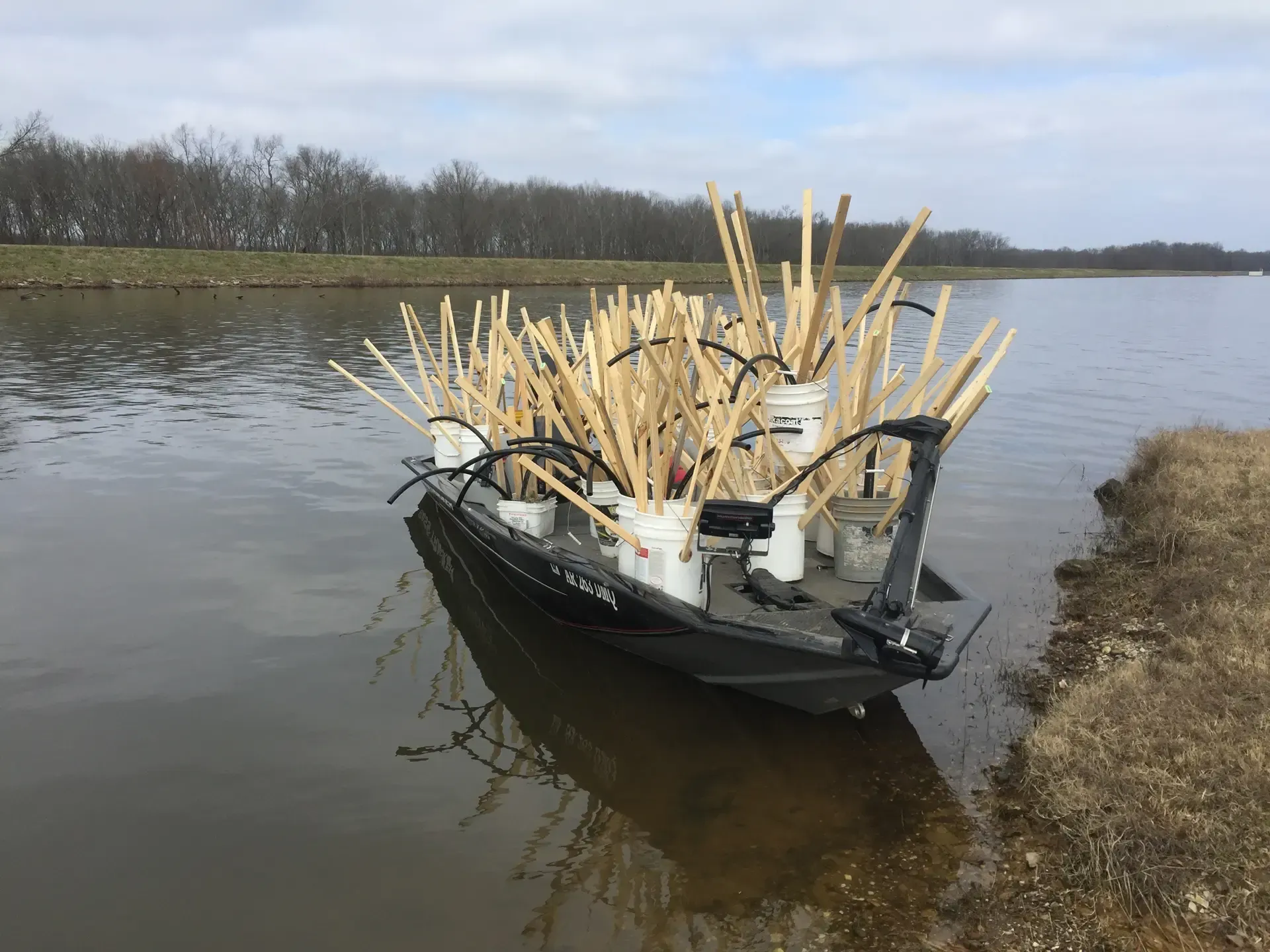 What To Expect Keeping It Crappie Guide Service Fishing Charter in Lake Dardanelle Arkansas A boat filled with buckets and sticks is floating on top of a body of water.