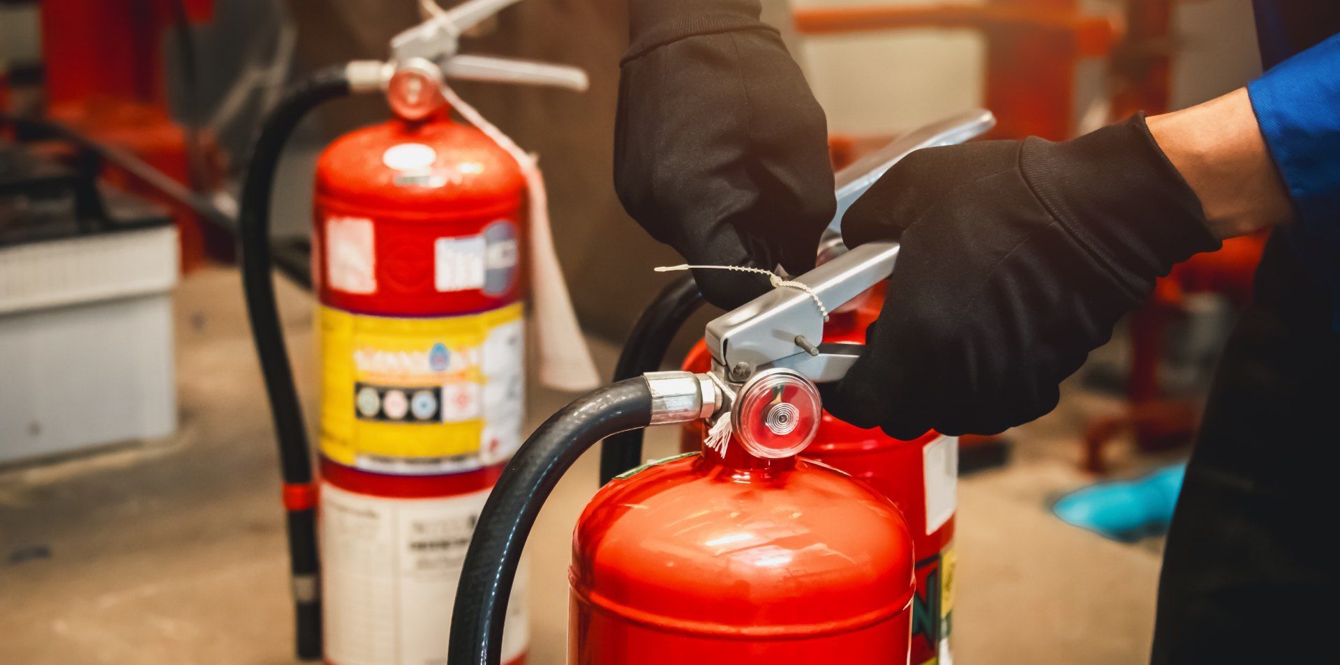 A person wearing black gloves is holding a fire extinguisher.