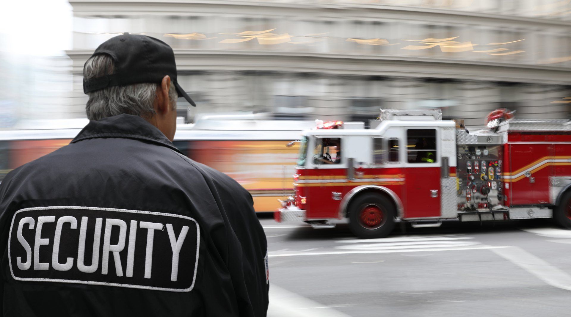 A security guard watches a fire truck drive down the street