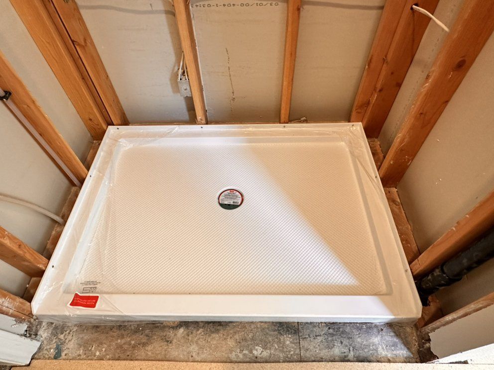 White shower base installed in a bathroom framed by wooden beams.