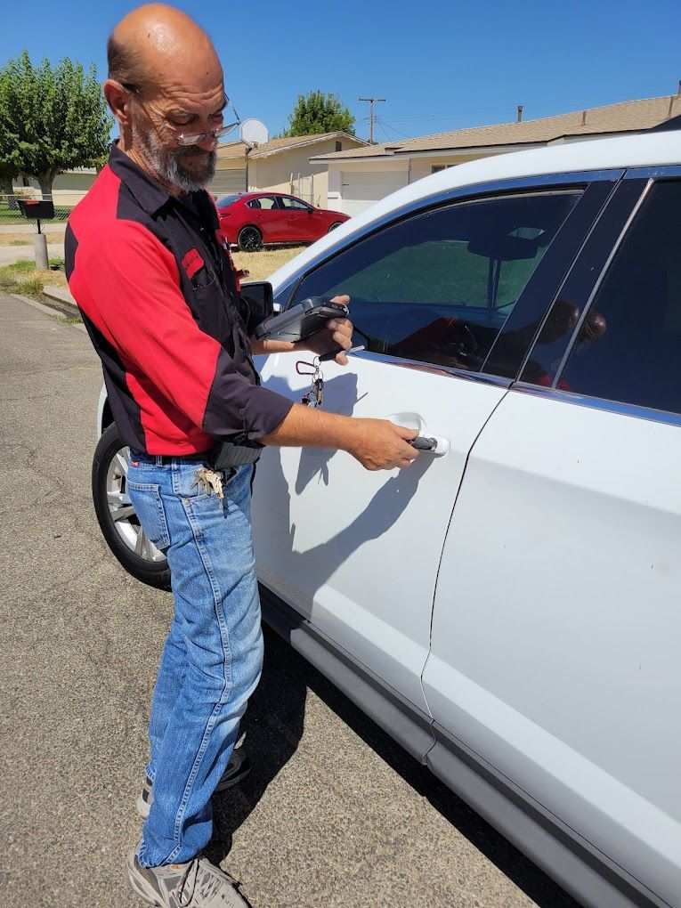 A man in a red shirt is standing next to a white car