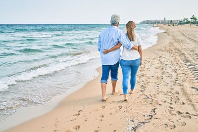 A man and a woman are walking on the beach.