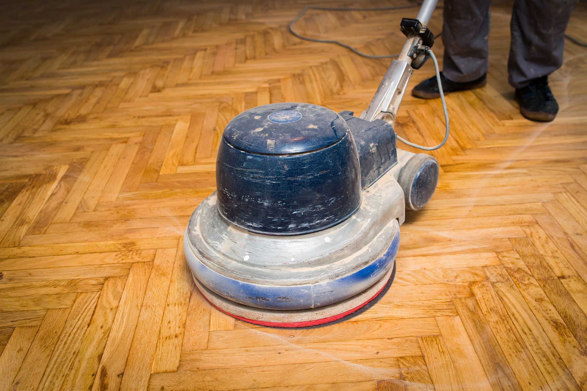Close-up of a man engaged in floor Buffing a wooden floor with a floor buffer.