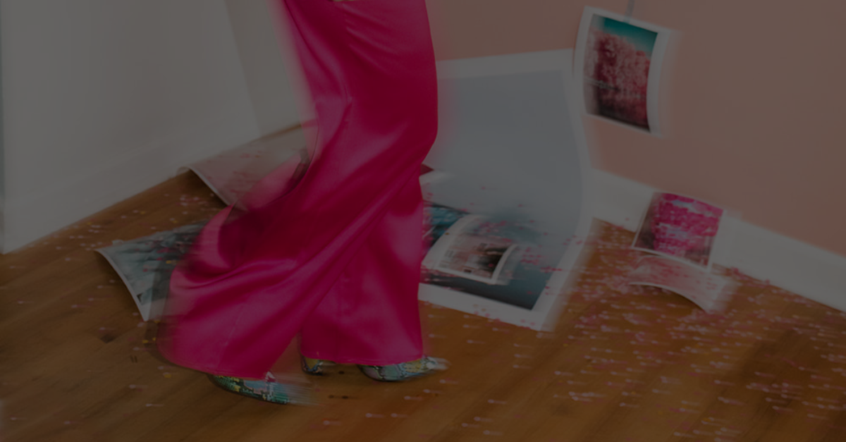 A woman in a pink dress is standing on a wooden floor.