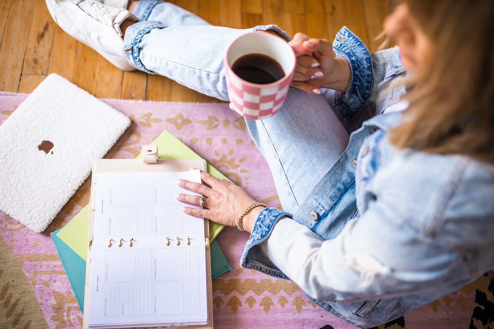 A woman is sitting on the floor holding a cup of coffee.