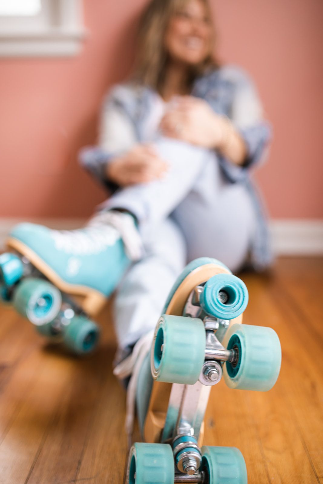 A woman is sitting on the floor wearing roller skates.