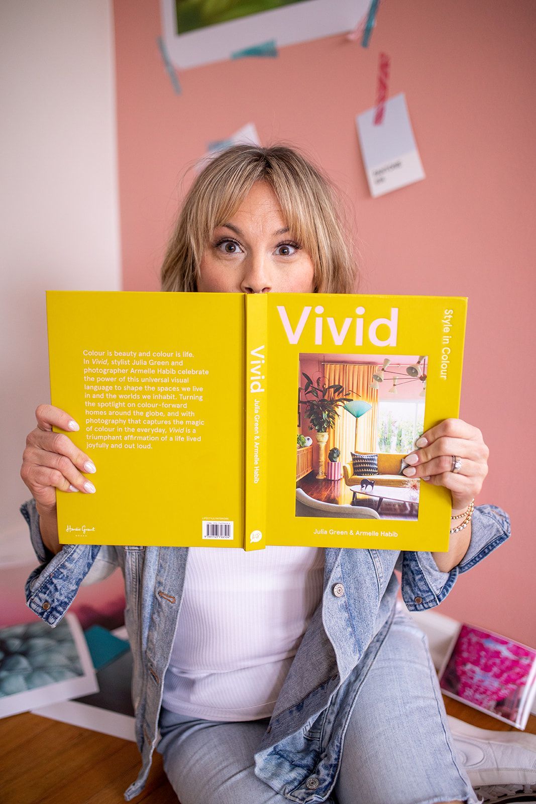A woman is sitting on the floor holding a yellow book.