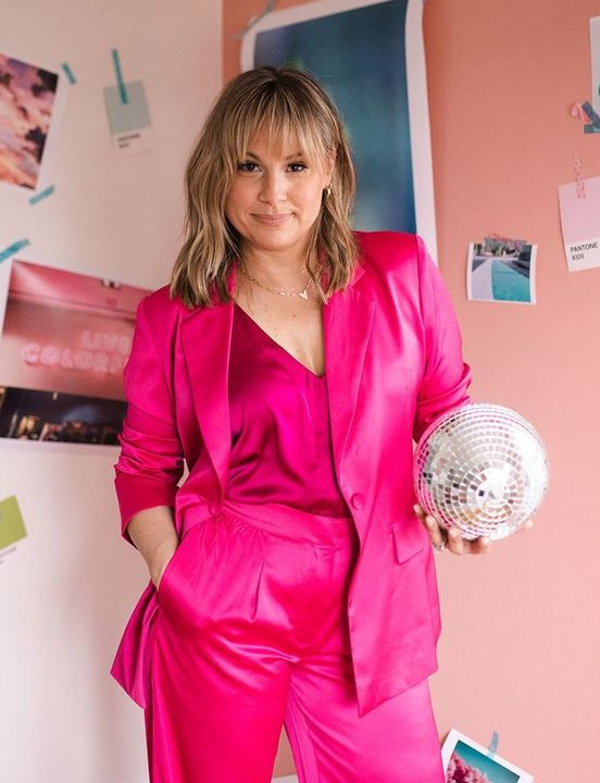 A woman in a pink suit is holding a disco ball.