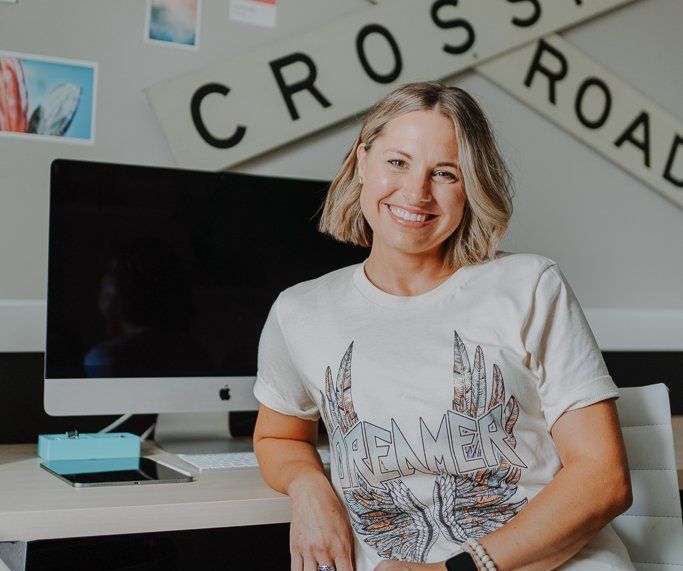 A woman is sitting in front of a crossroad sign