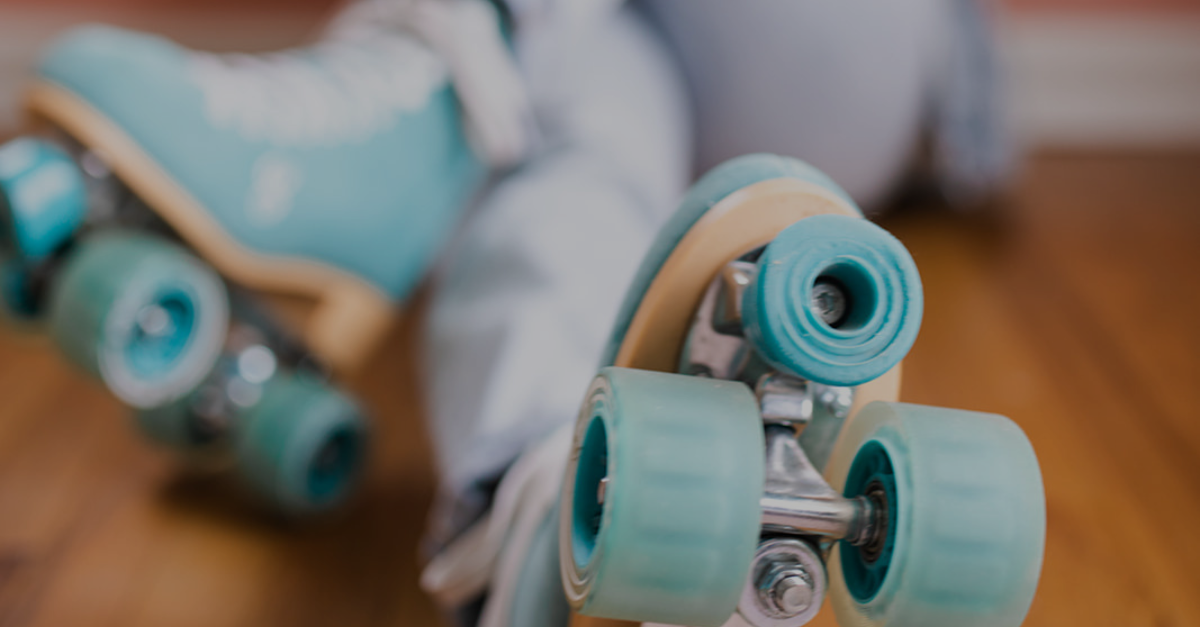 A person is wearing roller skates on a wooden floor.