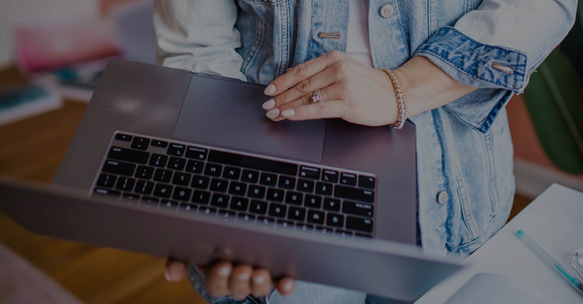 A woman is holding a laptop computer in her hands.