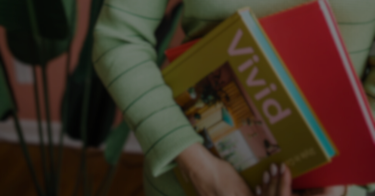 A woman is holding a stack of books in her hands.