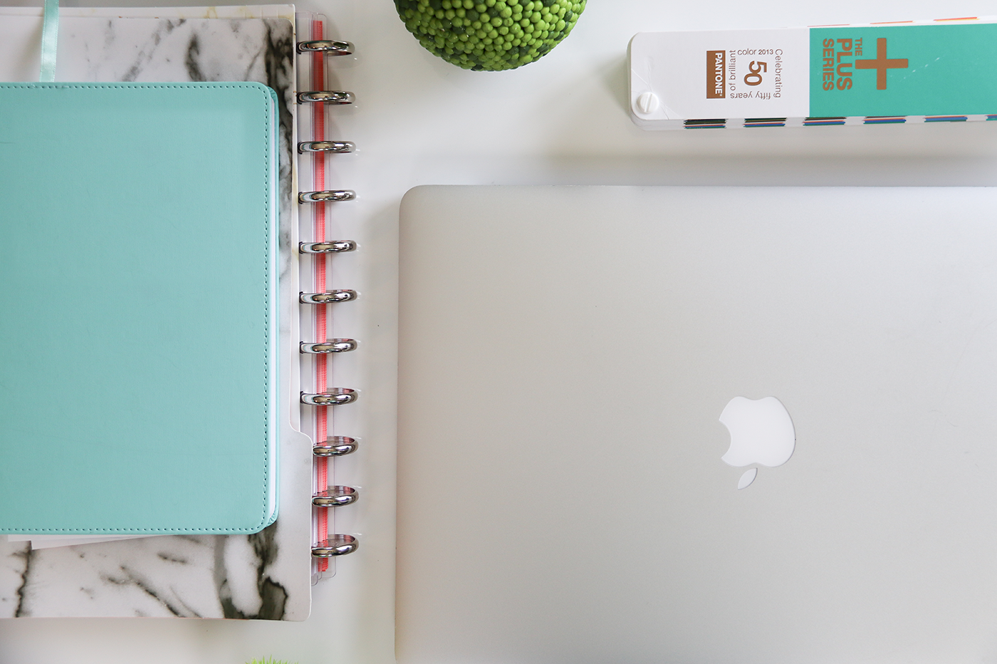 A laptop is sitting on a desk next to a notebook and a book.