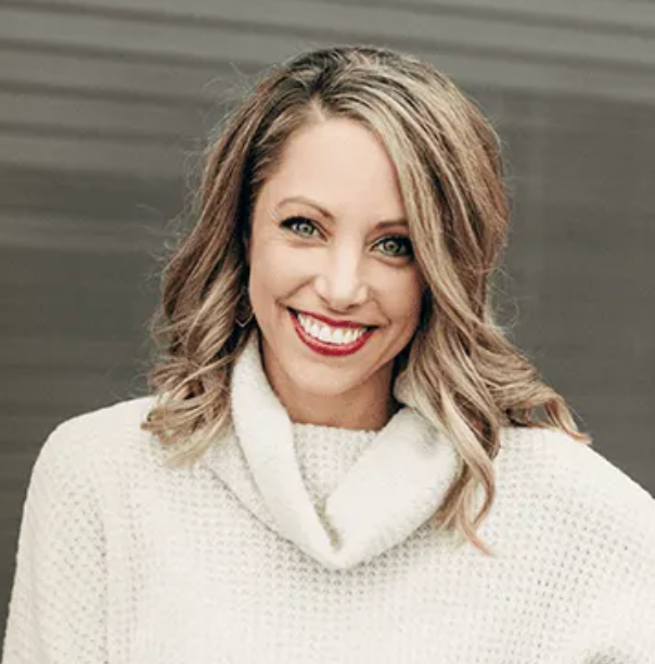 A woman wearing a white sweater and red lipstick is smiling.