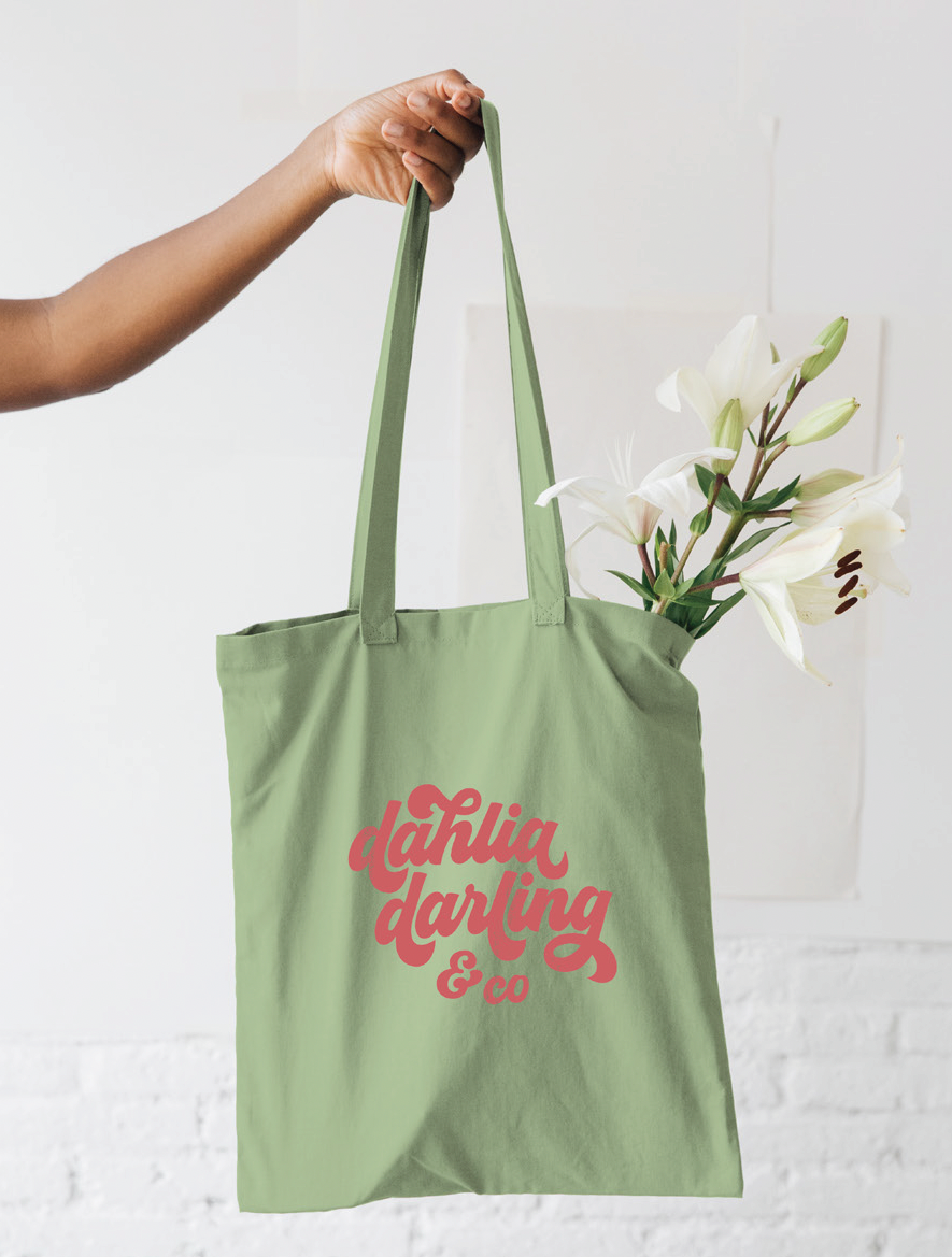A person is holding a green tote bag that says tahiti darling