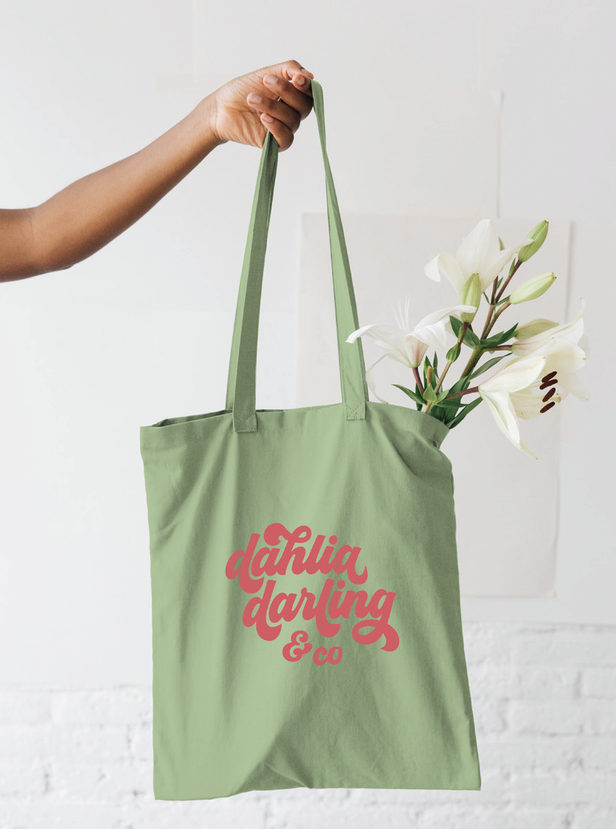 A person is holding a green tote bag that says tahiti darling