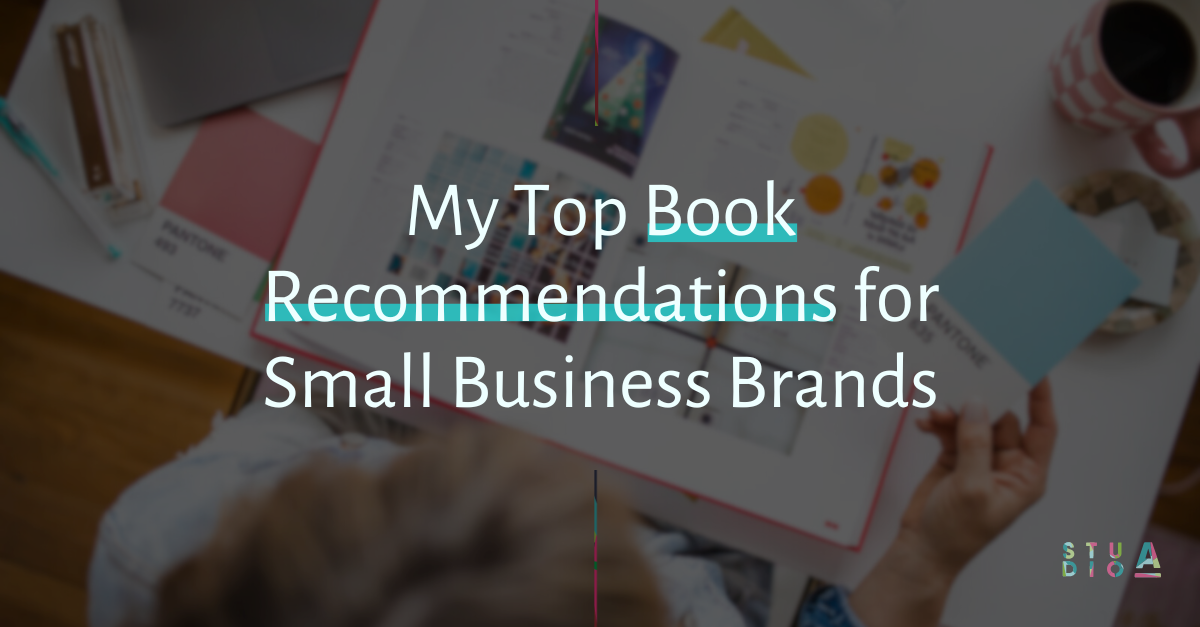 A person is sitting at a table looking at a book titled my top book recommendations for small business brands