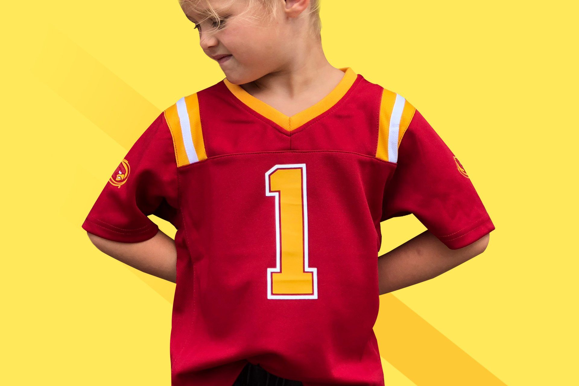 A young boy is wearing a red football jersey with the number 1 on it.