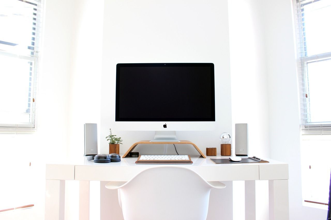 A white desk with a computer monitor on top of it