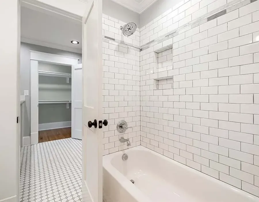 White subway-tile bathroom with a bathtub and open doorway to a closet.