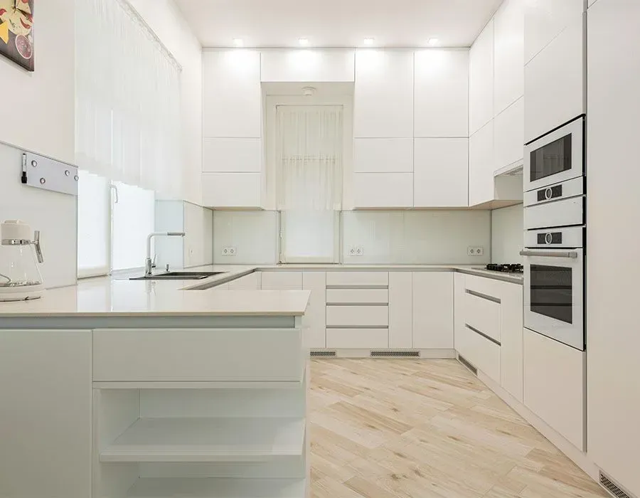Bright white modern kitchen with island, built-in ovens, and light wood floors