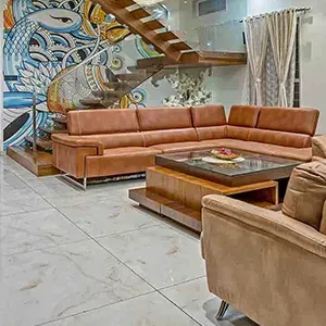 Modern living room with tan sectional, glass coffee table, spiral staircase, and mural wall