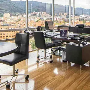 Modern office with black desks and chairs overlooking a city and mountains through large windows