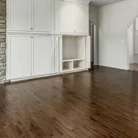 Empty room with dark hardwood floors and white built-in cabinets along one wall