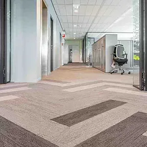Modern office hallway with patterned carpet, glass walls, and a rolling chair on the right.