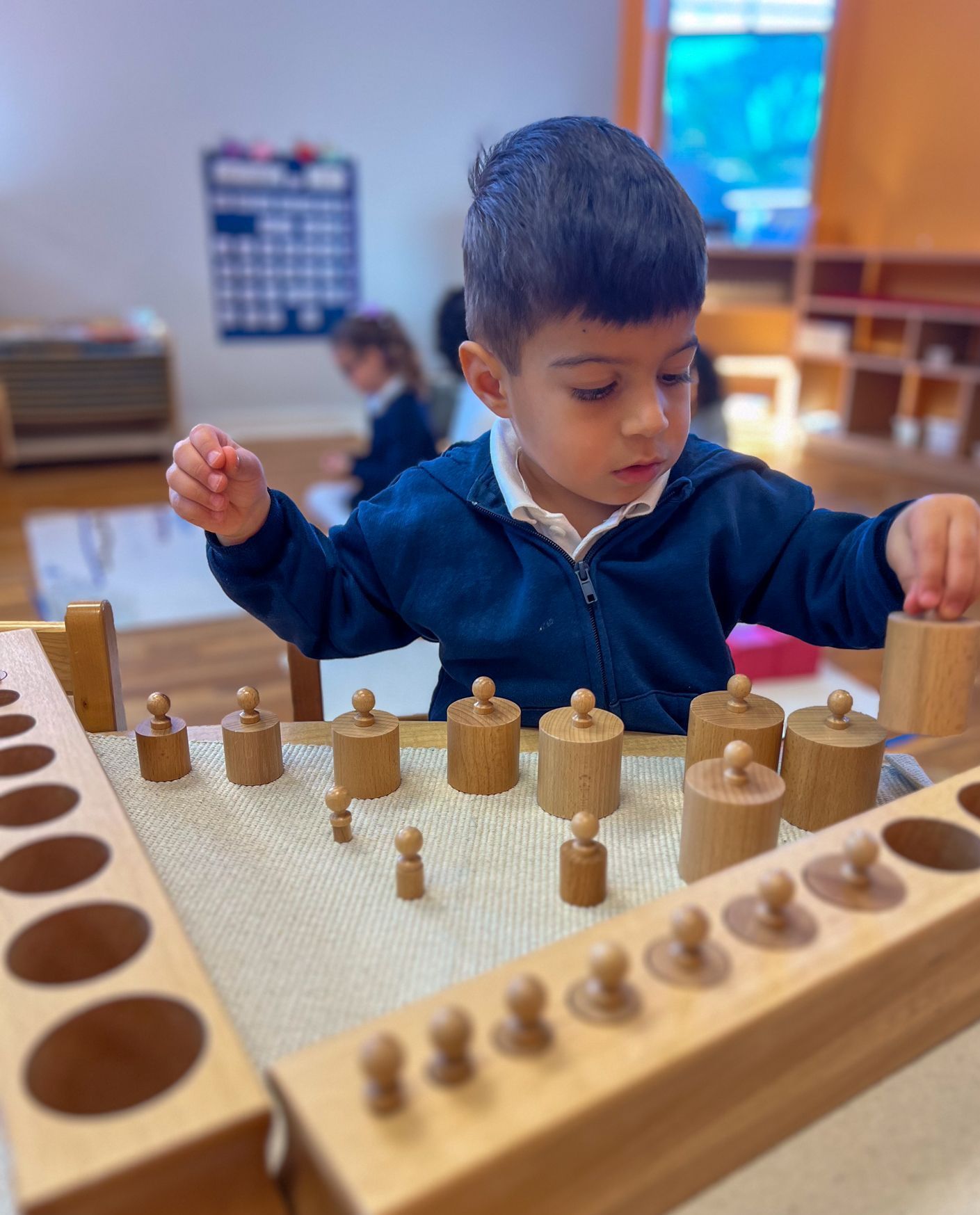 Child working with Montessori  cylinder blocks