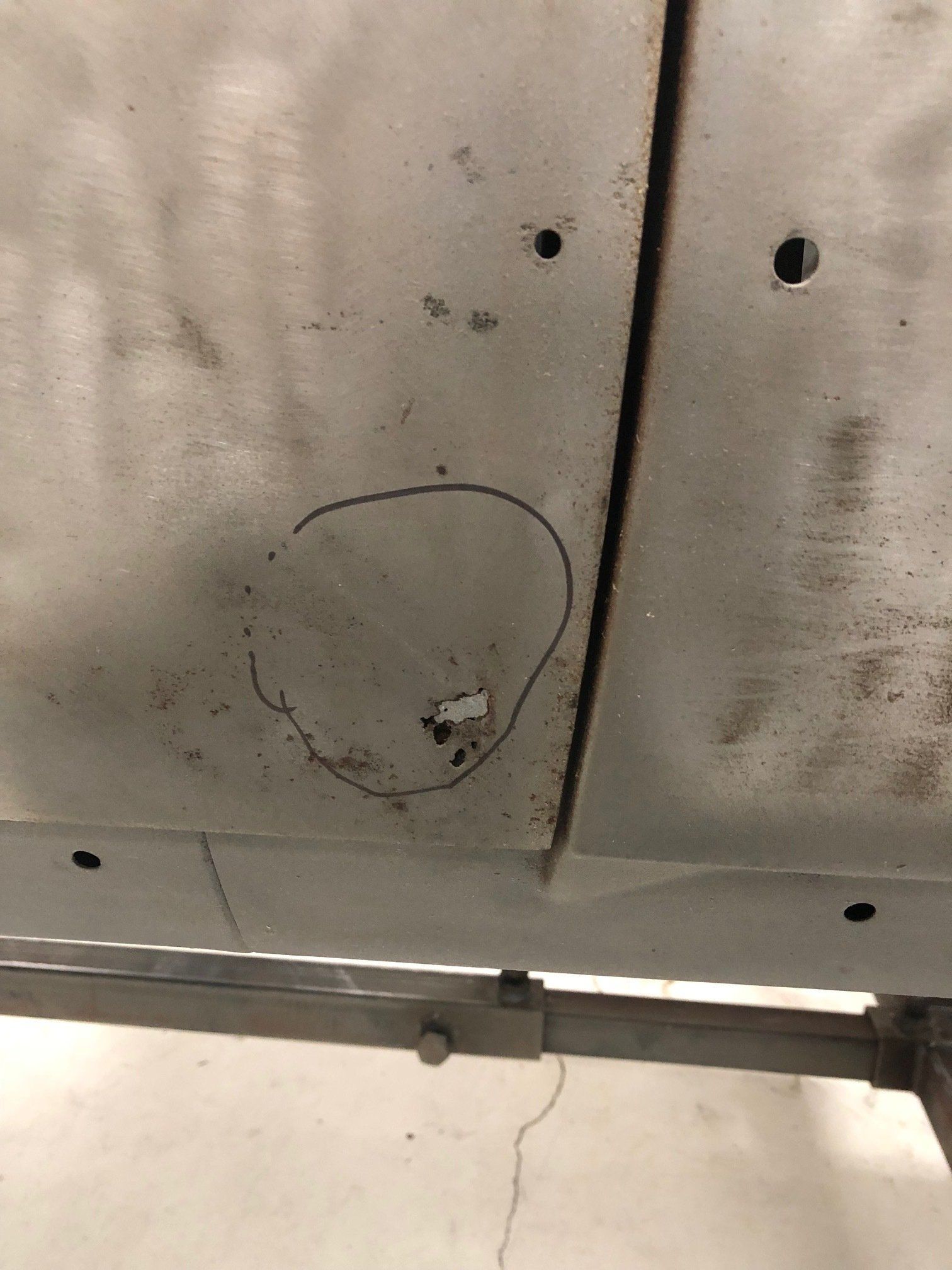 Close-up of a stained, cracked ceiling panel with holes and a visible seam.