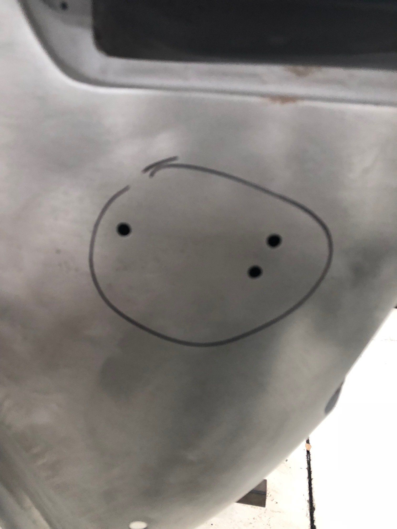 White fabric with a hand-drawn oval face and three black dots, possibly a simple sketch or marking.