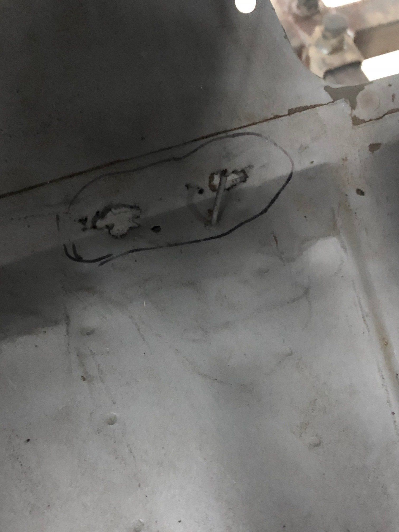 Circular outline on a gray floor around two small marks near a wall.