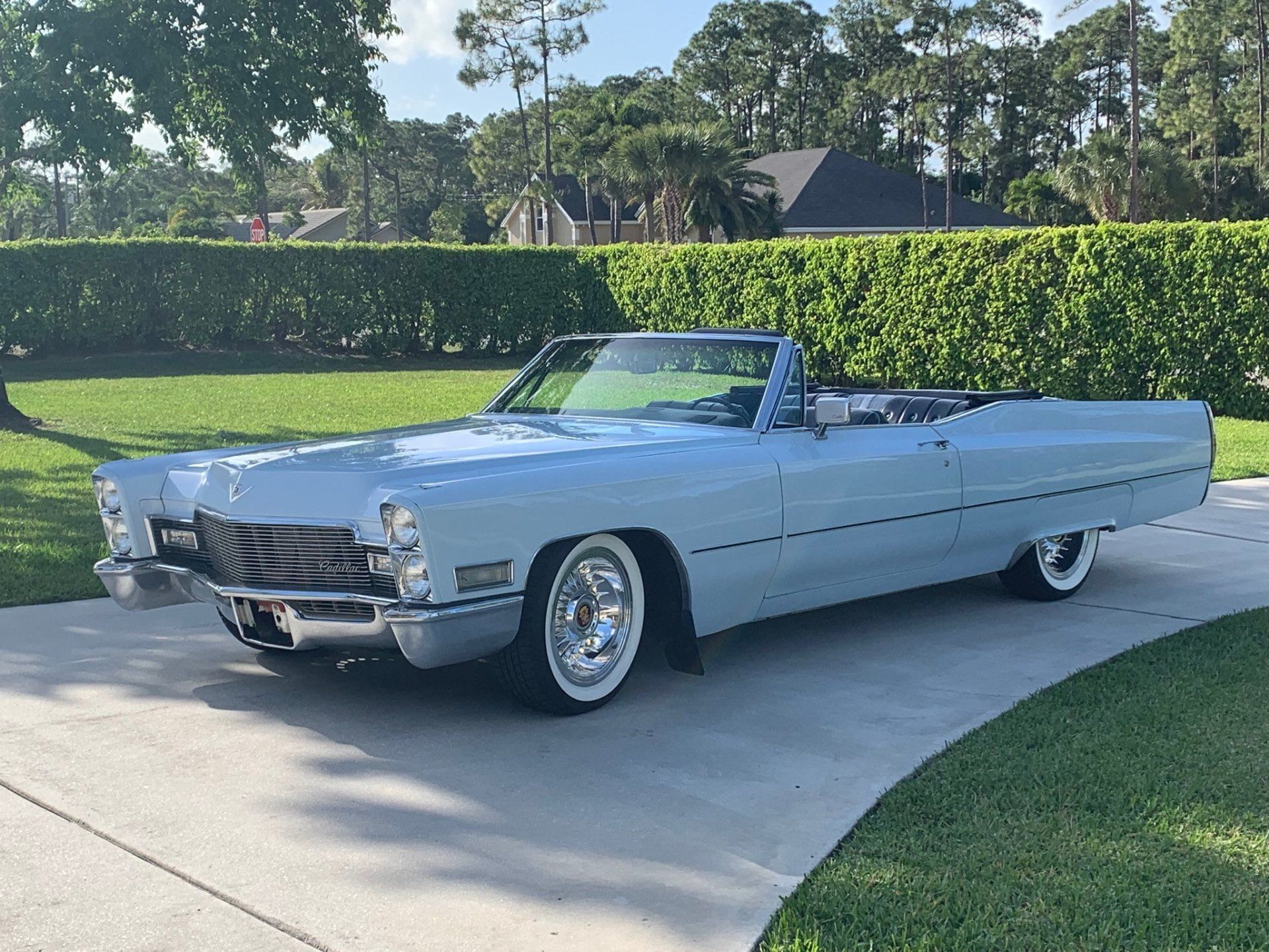 Light blue vintage convertible parked on a driveway beside a green lawn