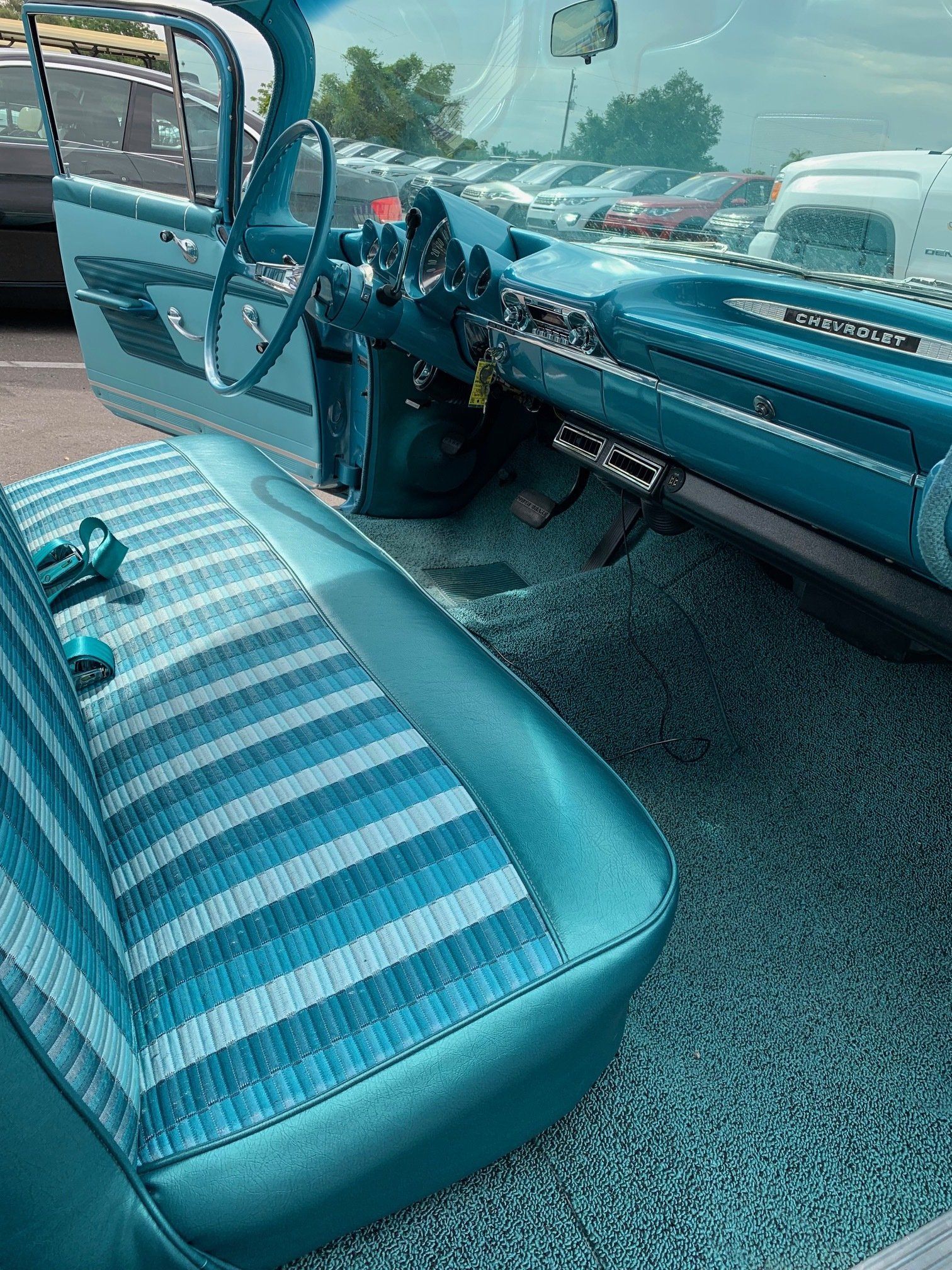 Blue vintage car interior with striped seats and dashboard, viewed from the passenger side