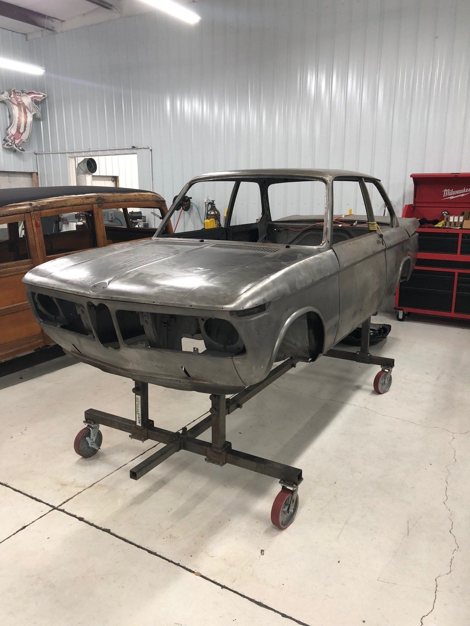 Rusty stripped car body on a rolling stand in a workshop garage