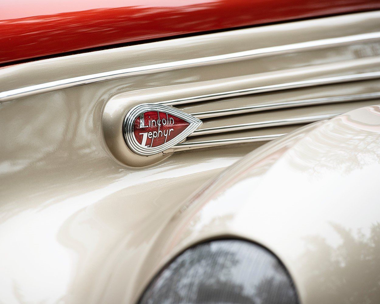 Close-up of a cream vintage car with red detailing and chrome trim